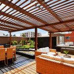 EMDS-Agence Publicitaire Terrasse moderne sur le toit avec pergola, meubles en osier et barbecue intégré.
